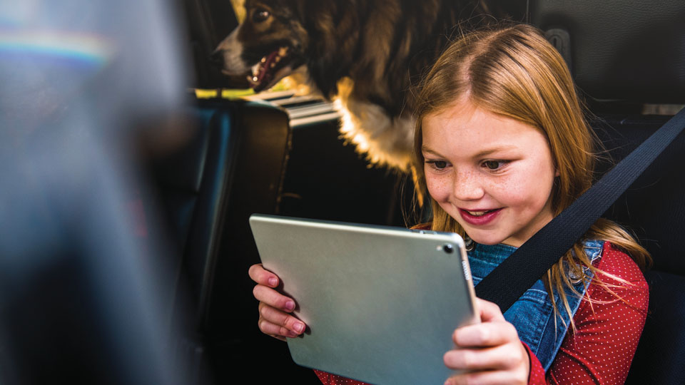 Una niña mirando DISH en una tableta en un auto